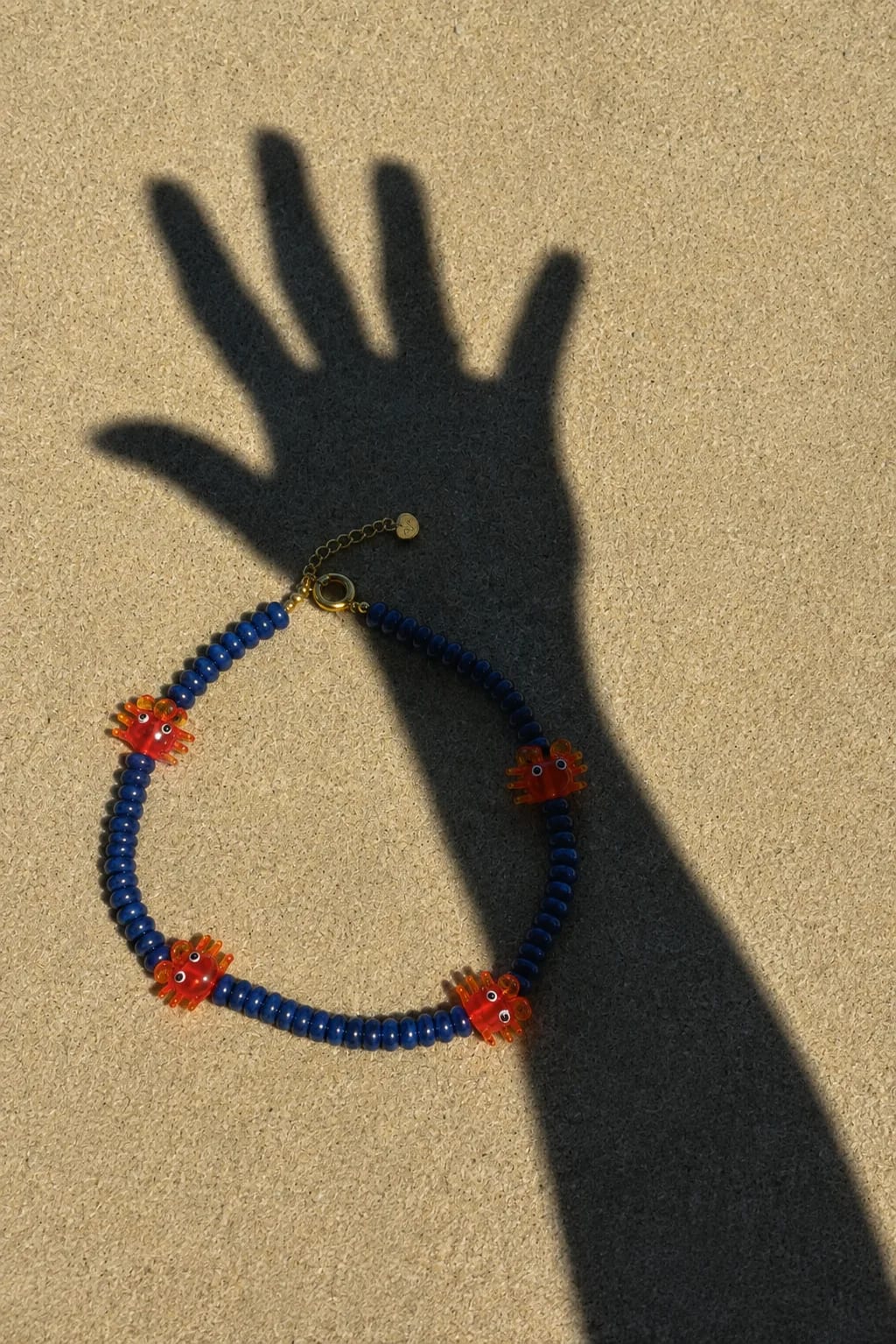 collier-perles-bleues-crabes-ombre-sable-plage